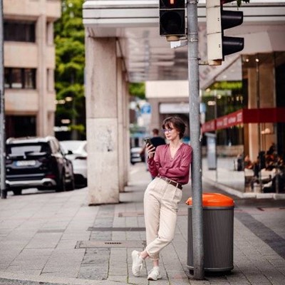 PHONE, LIGHTS, TRASHCAN, ORANGE, CAR, BELT, BUILDING, LEANING, PEDESTRIAN, POLE, SIDEWALK, STORE
