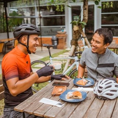 HELMET, GLOVES, PASTRY, BREAK, PHONE, BIKE, CYCLIST, COFFEE, REST, SADDLE, CUTLERY, NAPKIN