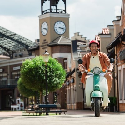 TREE, SCOOTER, BENCH, STRAP, RIDING, LIGHTS, HELMET, MIRRORS, CLOCK, TIME, SMILING, STREET