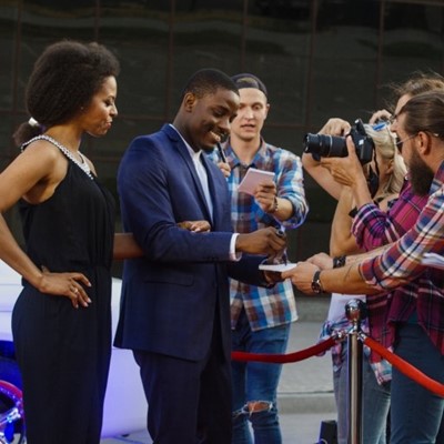 ROPE, PAPER, SIGNING, SUIT, DRESS, COUPLE, AUTOGRAPH, CELEBRITY, CAMERA, SMILING, FANS