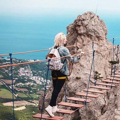 ROPE, BRIDGE, ROCK, SLATS, BUILDINGS, HEIGHT, HARNESS, BACKPACK, DENIM, WOOD, CABLES, SCENERY