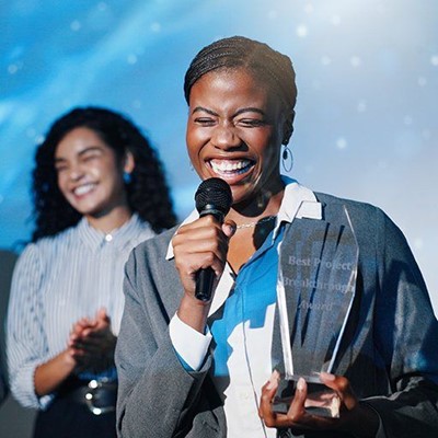 WINNER, HAPPY, BUCKLE, GLASS, NECKLACE, AWARD, SPEECH, MICROPHONE, TROPHY, CEREMONY, SMILING
