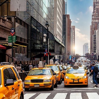 TAXIS, YELLOW, VEHICLES, SIGN, STREET, PEDESTRIAN, CITY, BUSSTOP, BUILDINGS, CLOUDS, HEADLIGHTS