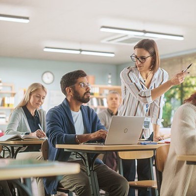 TEACHER, DESKS, POINTING, TEXTBOOK, CLOCK, STUDENTS, LAPTOP, EDUCATION, LEARNING, BANGLE, ADULT