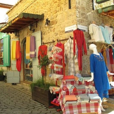 SHOP, BLANKETS, COATHANGER, SIGN, DISPLAY, DRESS, STREET, CLOTHING, PLANTER, SHUTTERS, STONEWORK