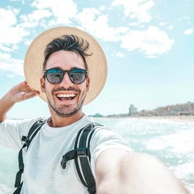 SHADES, OCEAN, BACKPACK, SMILING, WAVES, SELFIE, COASTLINE, BEARD, VACATION, TOURIST, CLOUDS, STRAPS